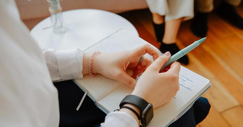 An individual jotting down notes in a notebook using a pen.