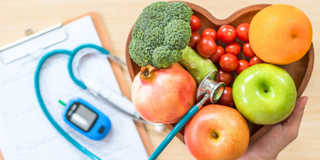 A person holding a stethoscope and a bowl of fruits and vegetables.