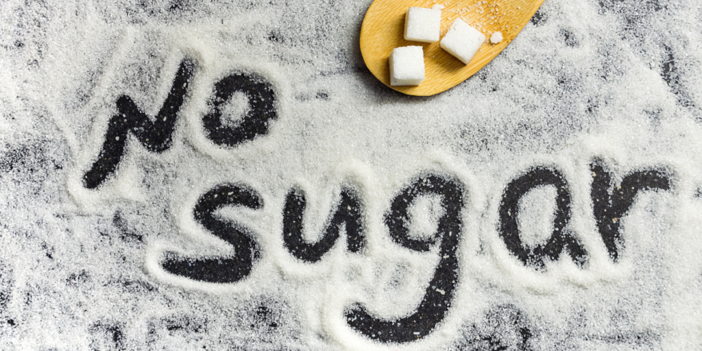 Image of sugar grains, 'no sugar' spelled out, and sugar cubes on table.