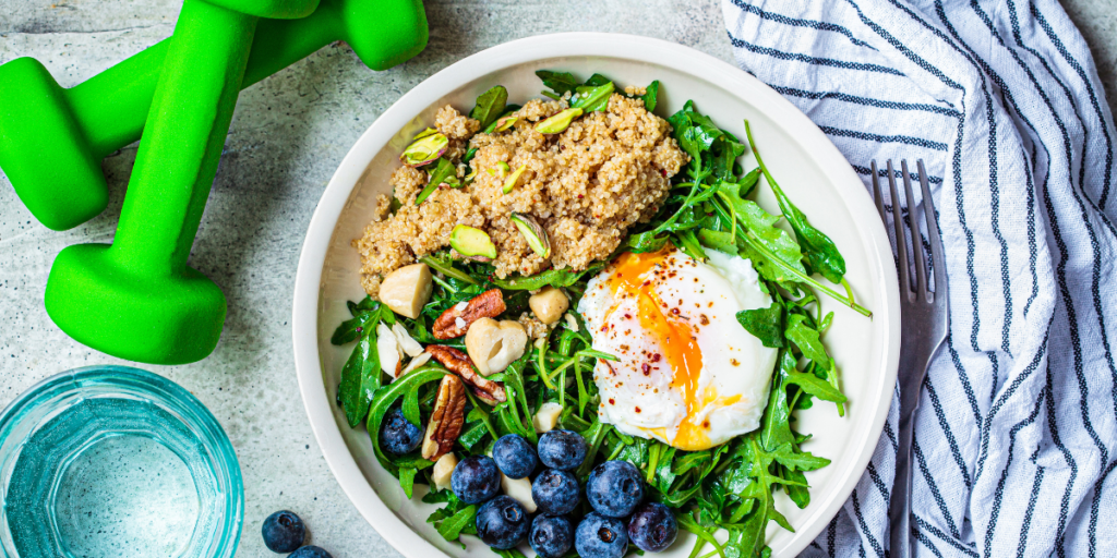 Plate of food with blueberries, eggs, and a green dumbbell on the side.