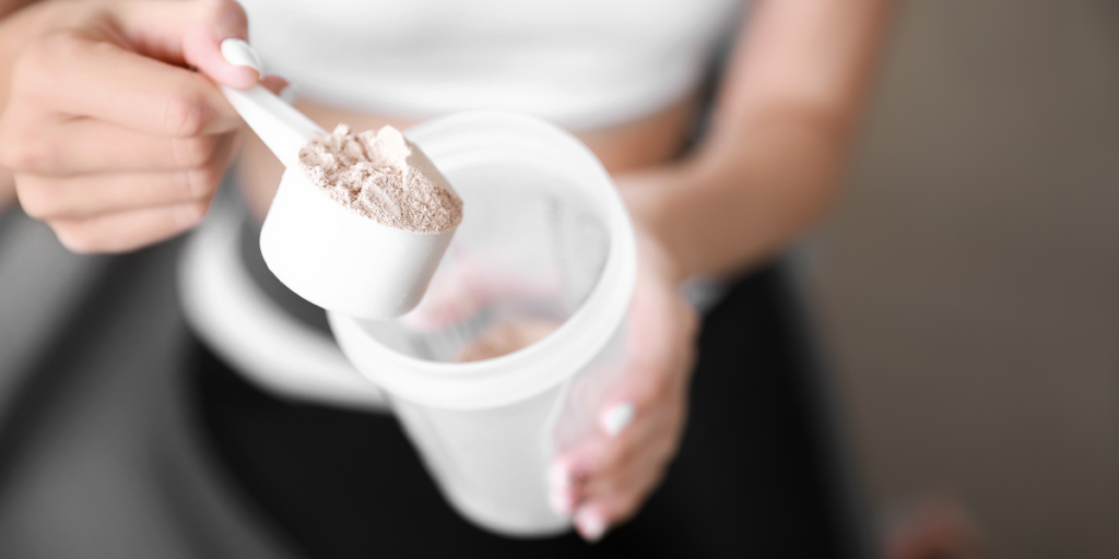 A woman holding a scoop of protein powder.